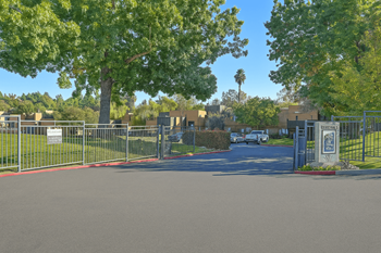 A gated entrance to a residential area with a sign on the gate.
